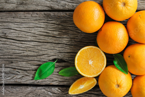 fresh orange fruits with leaves on wooden table.