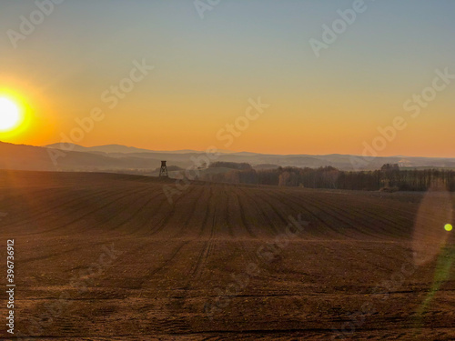 Autumn field covered with late sun and hunting stand in Novohradske hory, Bohemia, Czechia.