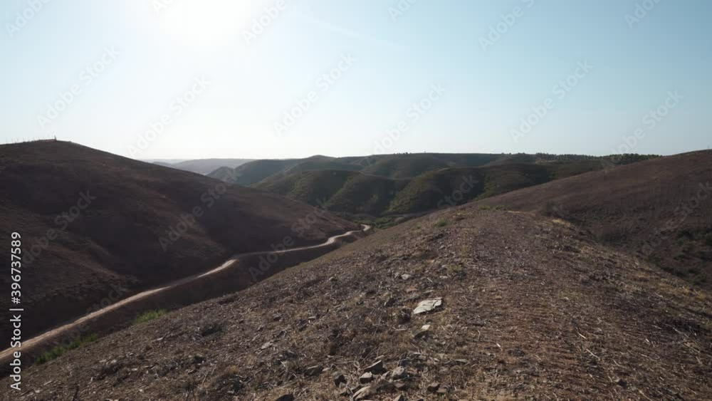 Dirt trails and barren hills in the harsh landscape of Algarve Portugal - Tilt up Reveal shot Dirt trails and barren hills in the harsh landscape of Algarve Portugal - Tilt up Reveal shot
