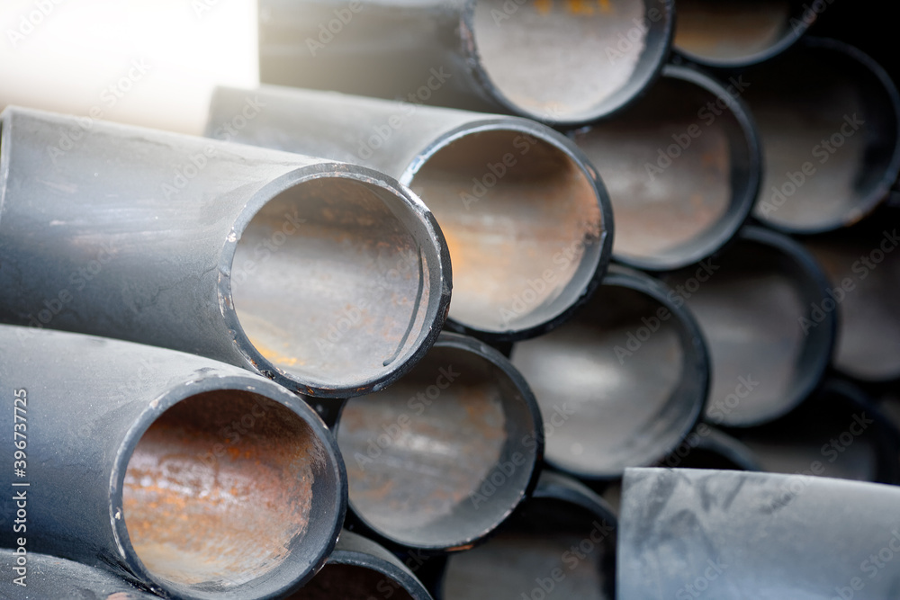 Black metal pipes and adapters of different diameters for gasification or water supply. Industrial background Black metal pipes and adapters of different diameters for gasification or water supply. Industrial background