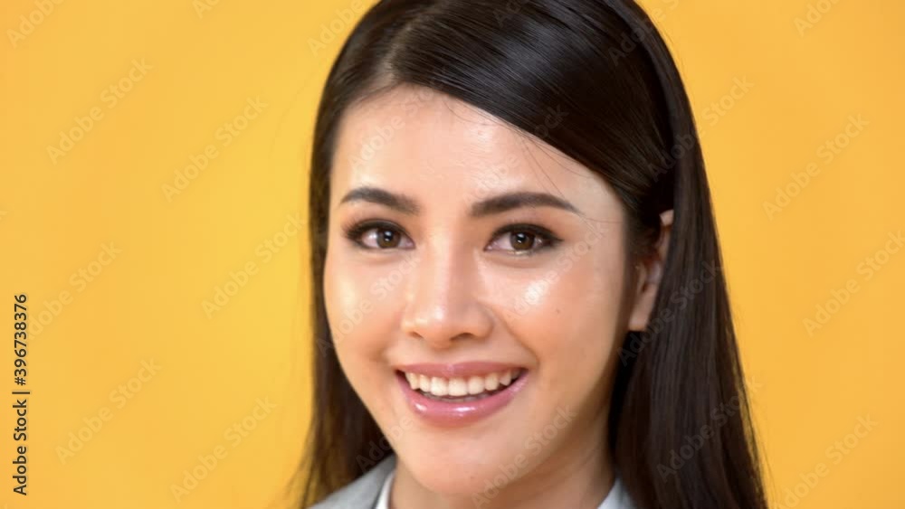 Close up of cheerful attractive Asian woman face smiling in isolated studio yellow background Close up of cheerful attractive Asian woman face smiling in isolated studio yellow background