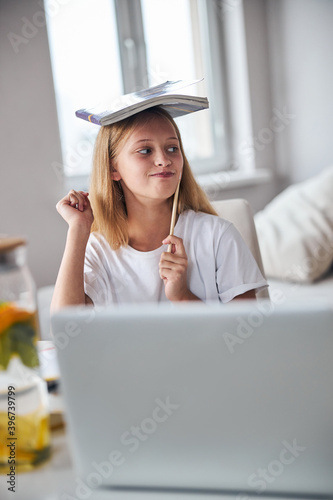 Naughty adolescent placing a book on her head