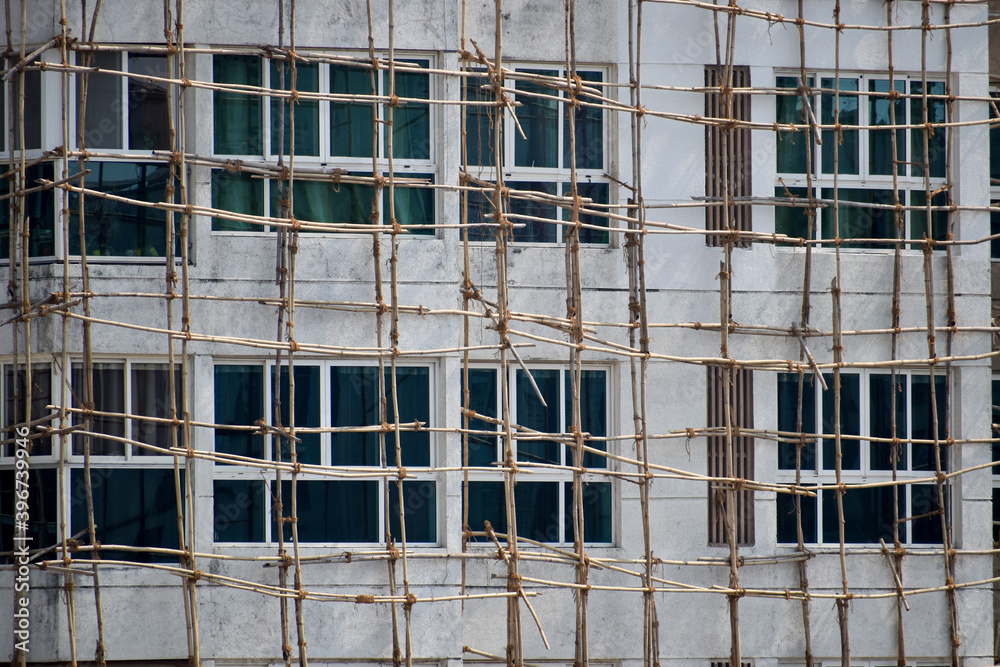 bamboo scaffolding on white building ,construction site . Bamboo tied with jute ropes