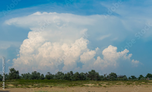 a big and fluffy cumulonimbus cloud in the blue sky © rostovdriver