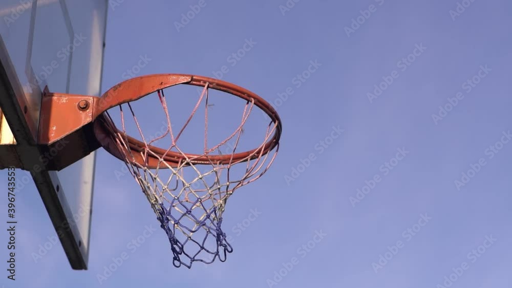 The ball flies into a basketball hoop against the background from clouds. The ball flies into a basketball hoop against the background from clouds.