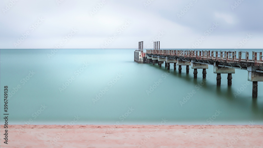 Minimalist fine art image of abandoned jetty extending out to the sea. Selective focusing on the jetty as the subject.