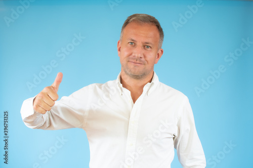 Happy man wearing white shirt with thumb up sign on blue background