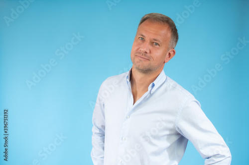 Handsome young man in casual shirt smiling over blue background. © Danko