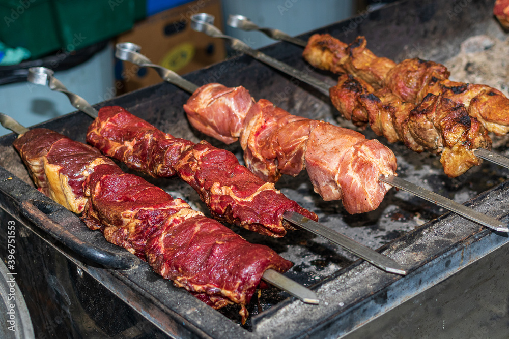 Meat products are cooked on the grill. Delicious food cooked over an open fire offered at a street food fair, event, festival.