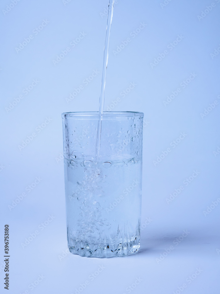Pouring water from a bottle into a glass on a blue background Pouring water from a bottle into a glass on a blue background