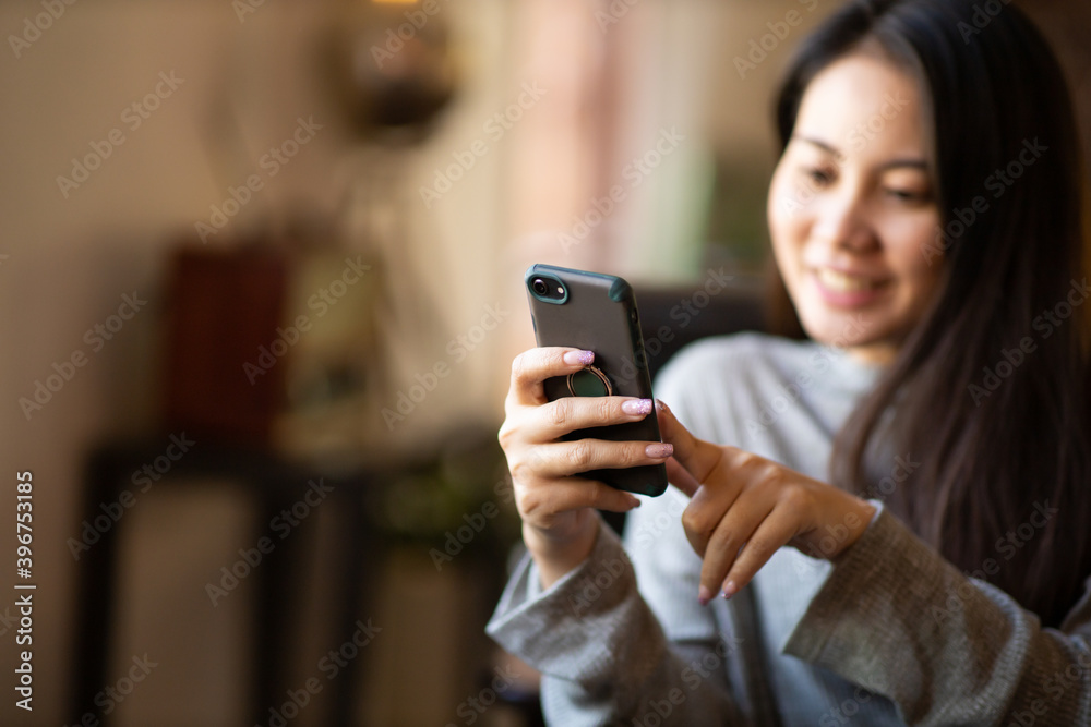 Closeup portrait young Asian beautiful woman smiling and using a smartphone for business or shopping online in coffee cafe Closeup portrait young Asian beautiful woman smiling and using a smartphone for business or shopping online in coffee cafe