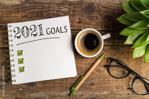 New year goals 2021 on desk. 2021 goals list with notebook, coffee cup, plant on wooden table. Resolutions, plan, goals, action, checklist,  idea concept. New Year 2021 template, copy space