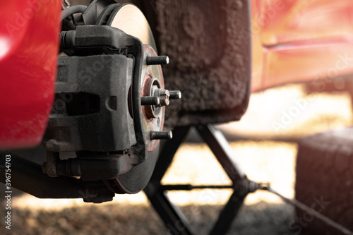 Front hub of a red car without a wheel close-up. A raised car with the wheel removed. The concept of puncturing a tire or replacing a summer wheel with a winter one with your own hands