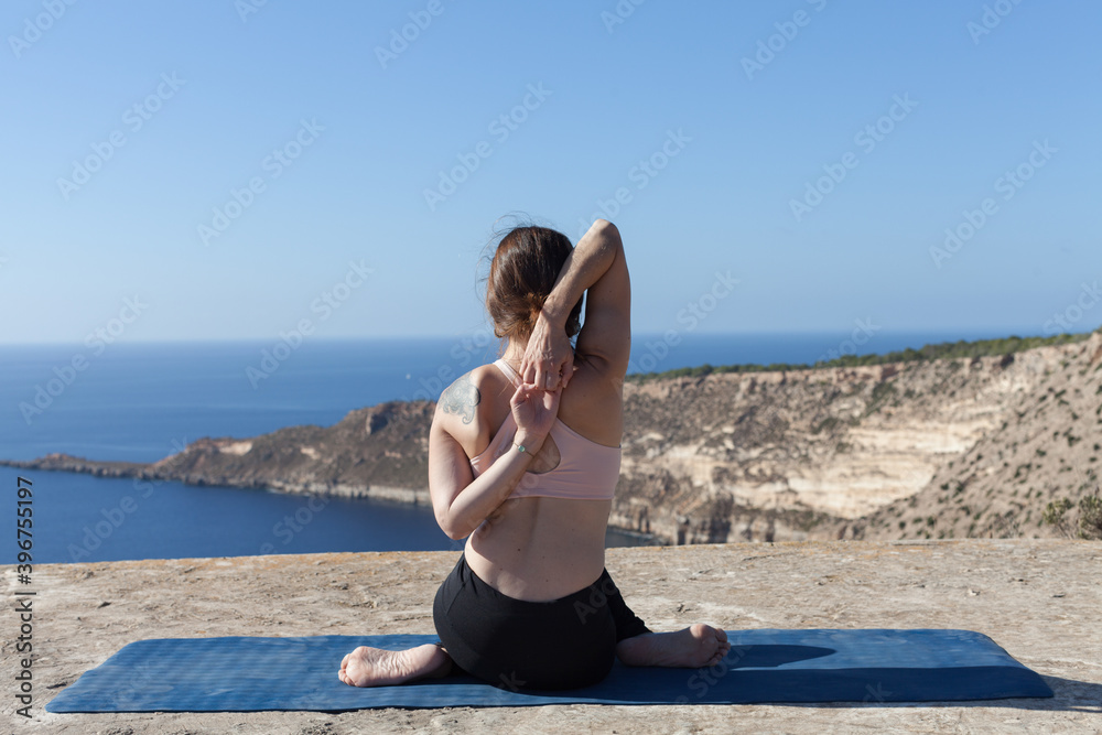 A yoga teacher holding a heart-shaped stone in her hands. The woman is in contact with the earth and prepares to meditate