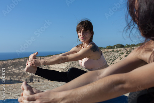 A yoga teacher holding a heart-shaped stone in her hands. The woman is in contact with the earth and prepares to meditate