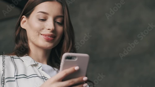 Young pregnant smiling brunette woman using mobile phone indoors at home