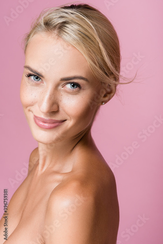 Фотография smiling beautiful blonde woman with freckles and bare shoulders isolated on pink