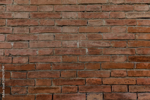 Beautiful brick wall with colorful red brown bricks uneven and cracked with space for texture background