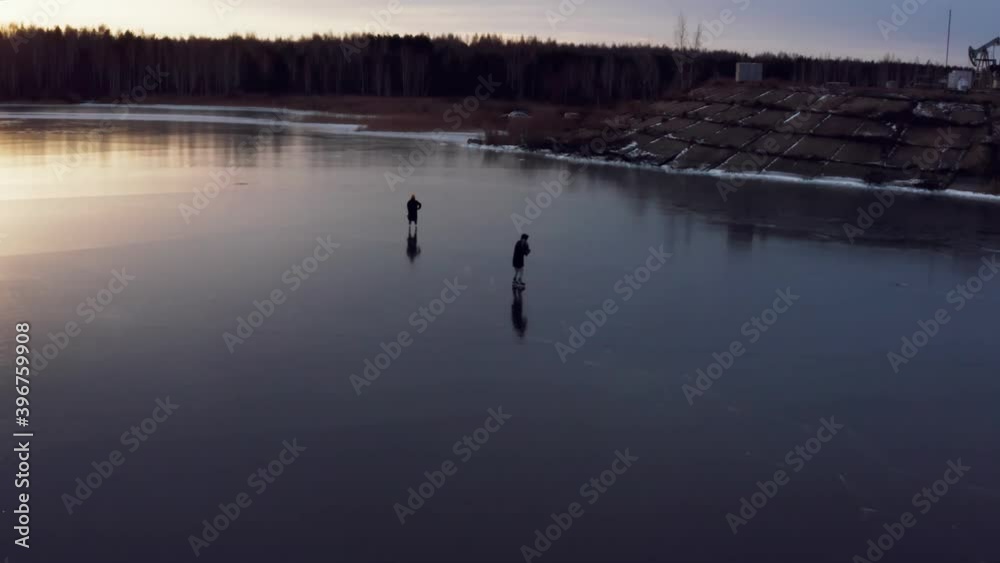 Two people go ice skating on a frozen lake in the morning Two people go ice skating on a frozen lake in the morning