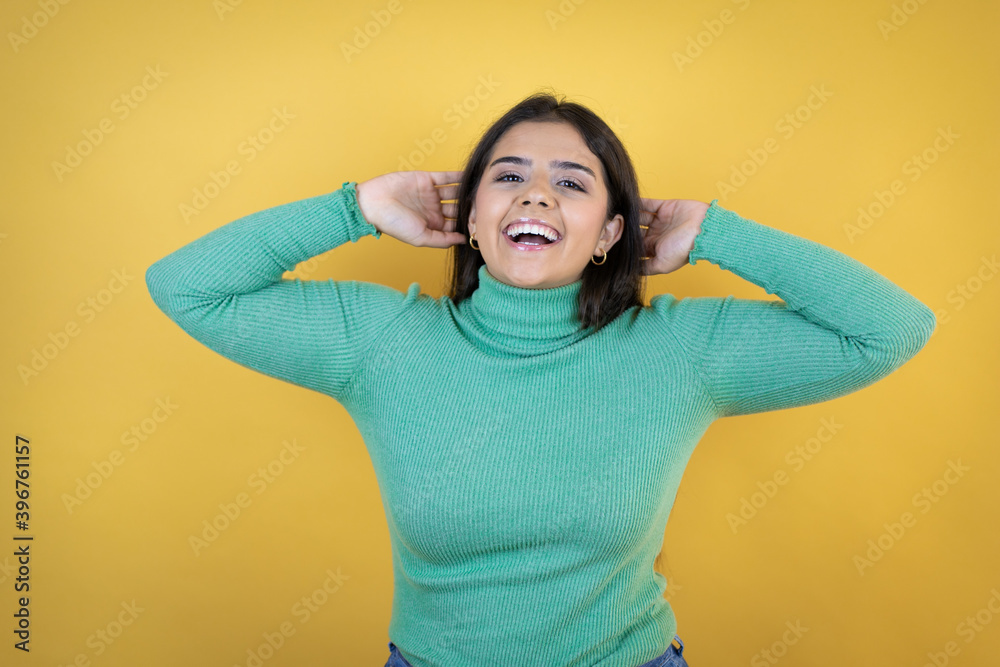 Young caucasian woman over isolated yellow background relaxing and stretching, arms and hands behind head and neck smiling happy