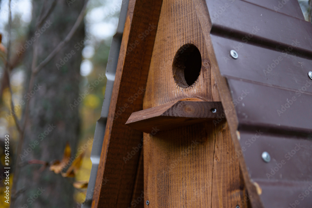 Closeup photo of brown wooden birdhouse with gabled roof on a tree in the park. A house for the birds. Bird feeder. Closeup photo of brown wooden birdhouse with gabled roof on a tree in the park. A house for the birds. Bird feeder.