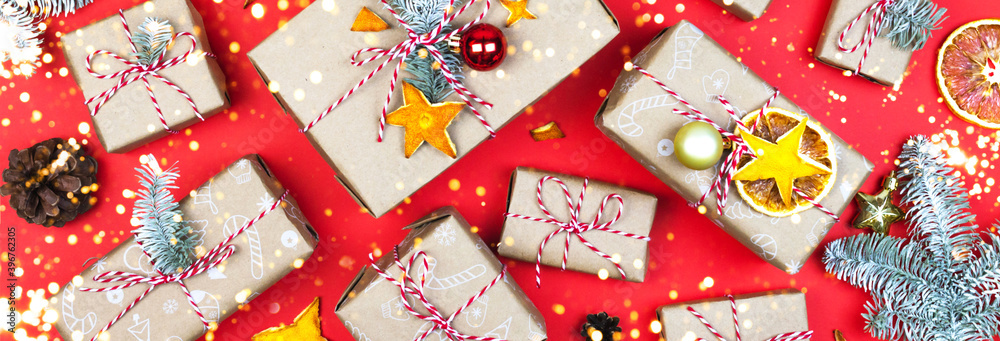 Many eco gift boxes on red background. New year banner template. Winter holiday packaging with garland lights Many eco gift boxes on red background. New year banner template. Winter holiday packaging with garland lights