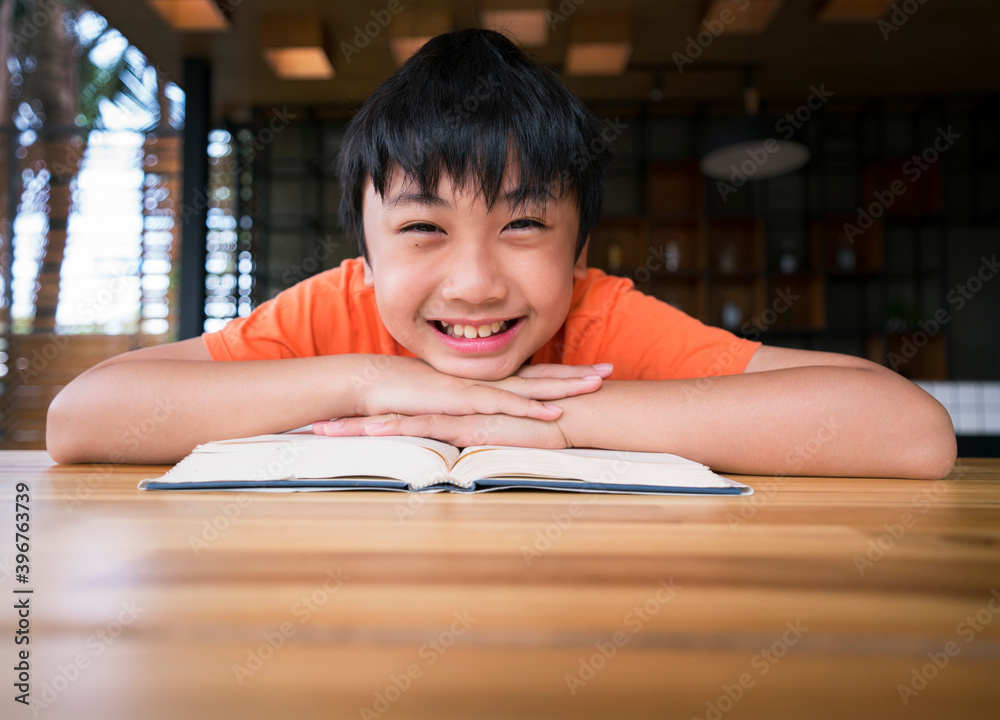Boy smiling with a book on wooden table. Learning at home Boy smiling with a book on wooden table. Learning at home