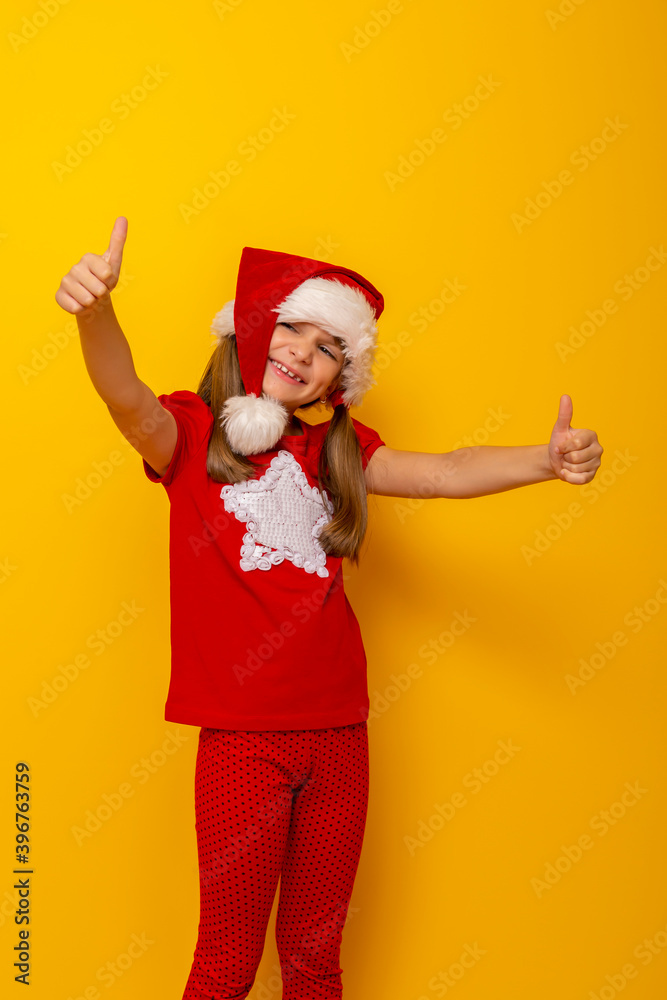 Child wearing Santa hat showing thumbs up
