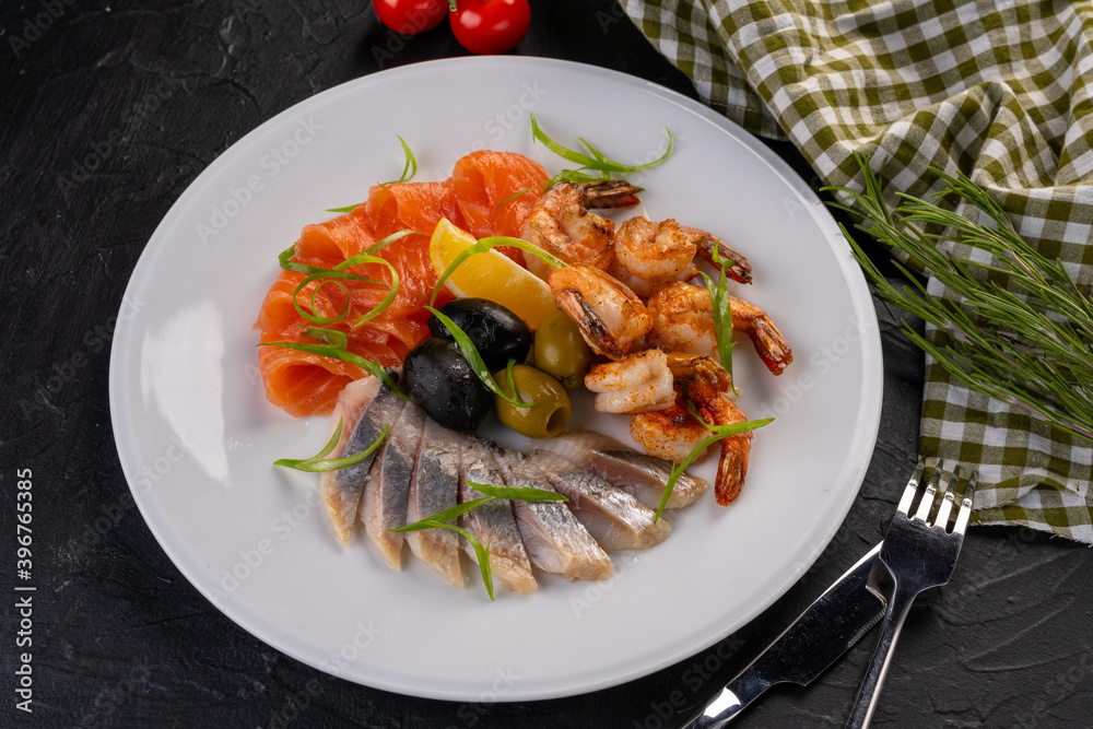 Seafood plate. seafood with olives and lemon on a white plate. grilled salmon, herring and tiger prawns with herbs and spices. Seafood plate. seafood with olives and lemon on a white plate. grilled salmon, herring and tiger prawns with herbs and spices.