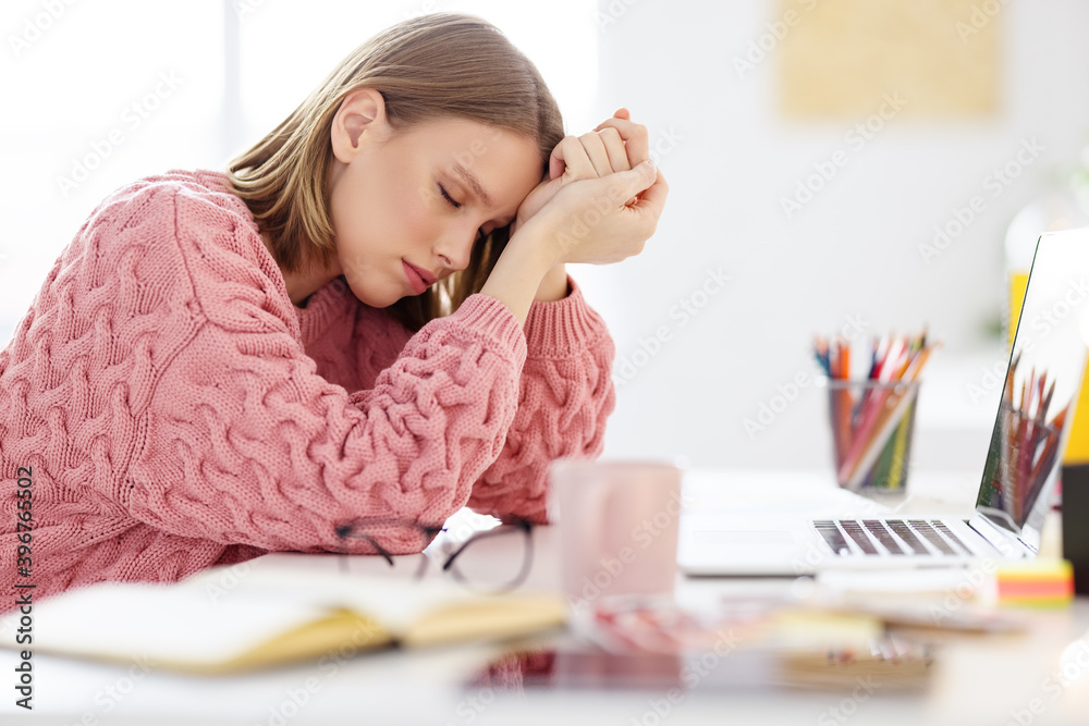 Tired woman sitting at table with laptop. Tired woman sitting at table with laptop.