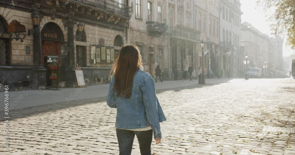 medium 4k shot of young dark haired woman walking down the street and exploring old beautiful city.Travel concept