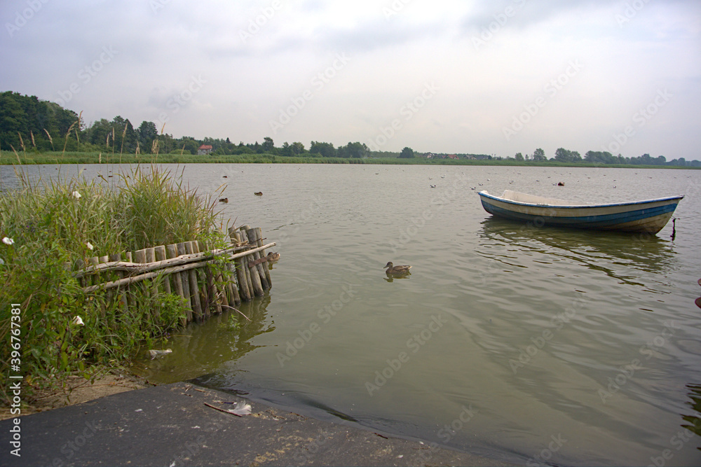 A fishing boat with ducks on a lake on a cloudy day