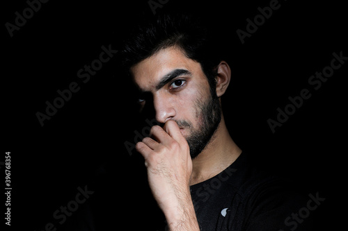 Expressive Thinking Portrait of young man with beard in black background 