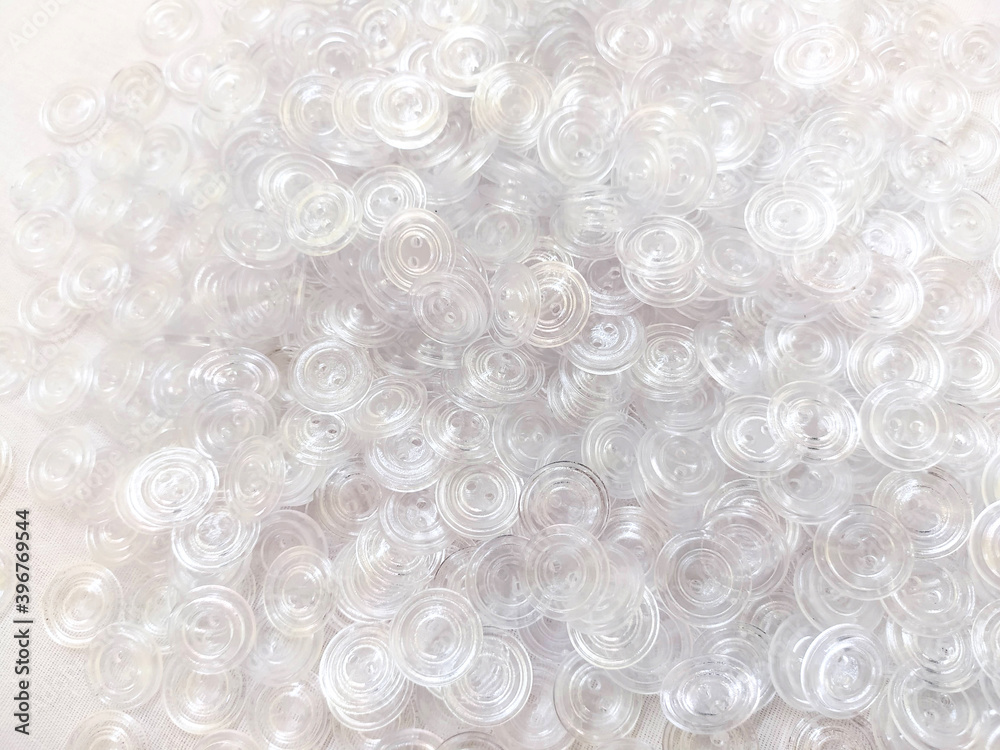 Lots of white transparent buttons for clothes. Background on the theme of light industry. Plastic round buttons Lots of white transparent buttons for clothes. Background on the theme of light industry. Plastic round buttons