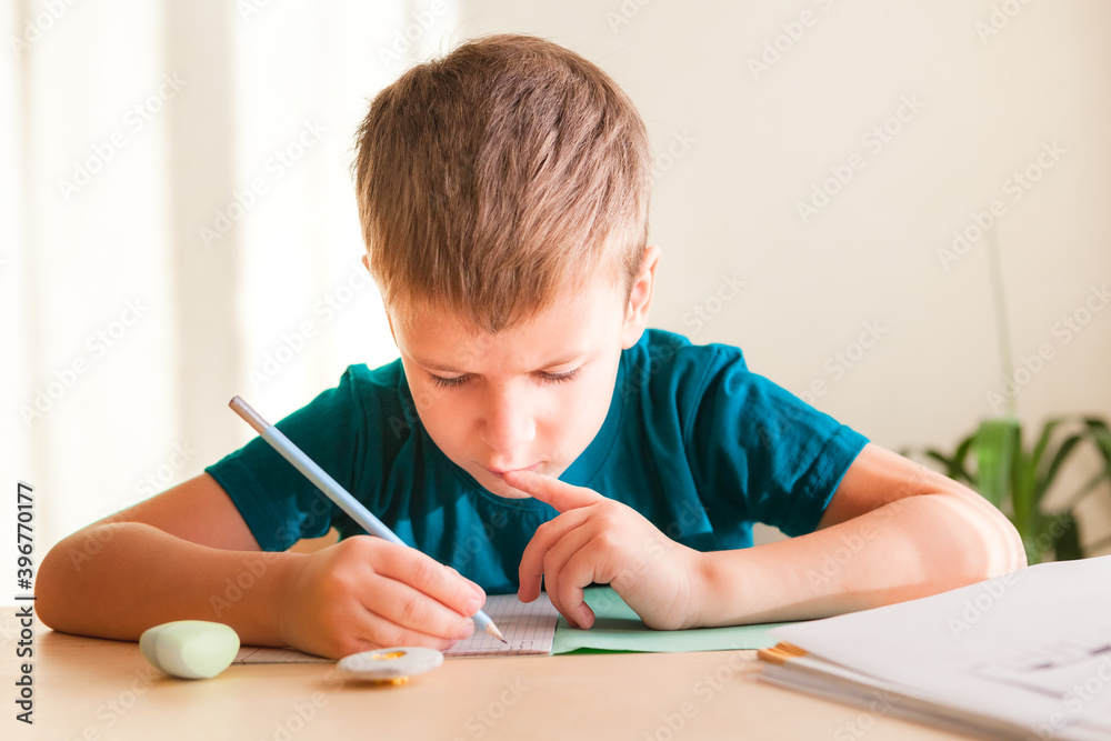 7 years old child boy doing lessons sitting at desk in his room. 7 years old child boy doing lessons sitting at desk in his room.