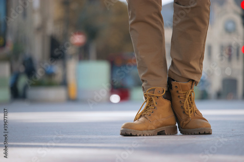 Unrecognizable man standing in the city center. Panoramic image close up of yellow winter boots. Street Photography December 2020. © CristianUrriaga
