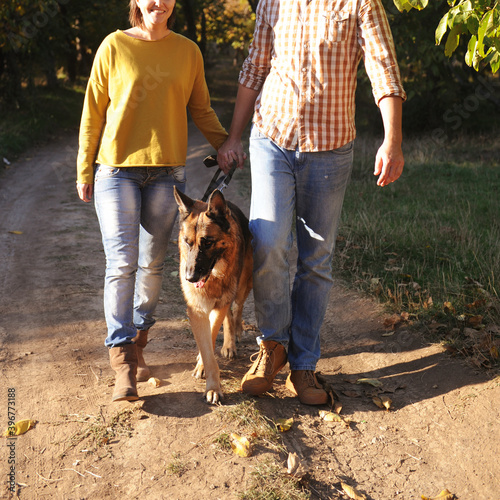 Happy love couple walking in park with their german shepherd dog