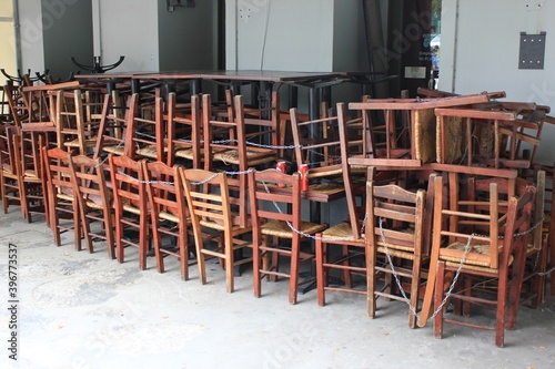 Chairs, tables and other furniture stacked outside closed cafe-restaurant due to Covid-19 lockdown - Athens, Greece, November 3 2020. photo