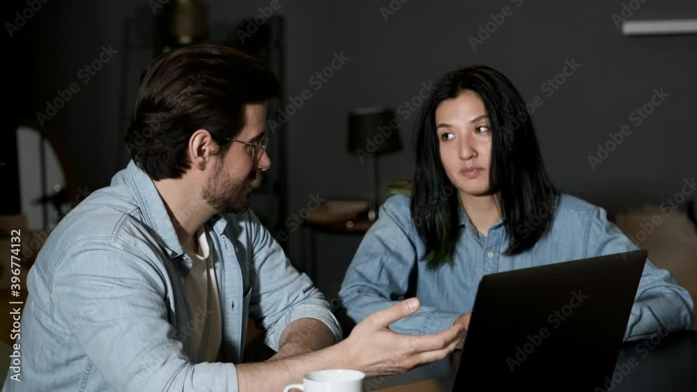 Portrait young couple sitting in front of a notebook at home. Handsome brunette man and cute woman working at laptop. Portrait young couple sitting in front of a notebook at home. Handsome brunette man and cute woman working at laptop.