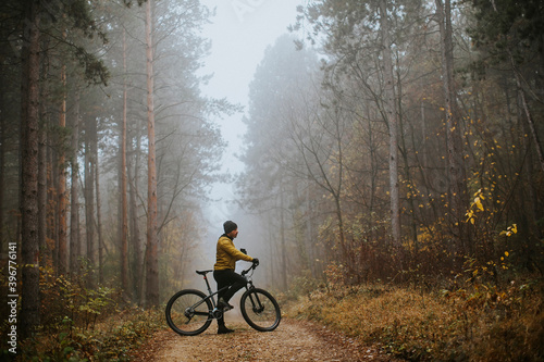 Fototapeta Naklejka Na Ścianę i Meble -  Young man taking a brake during biking through autumn forest
