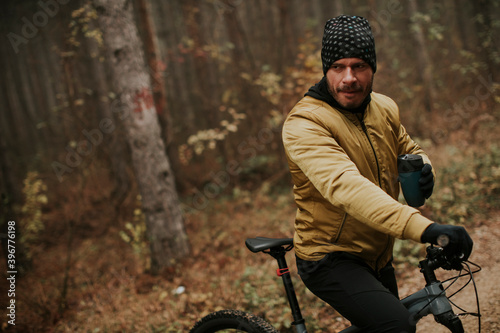 Young man taking a brake during biking through autumn forest