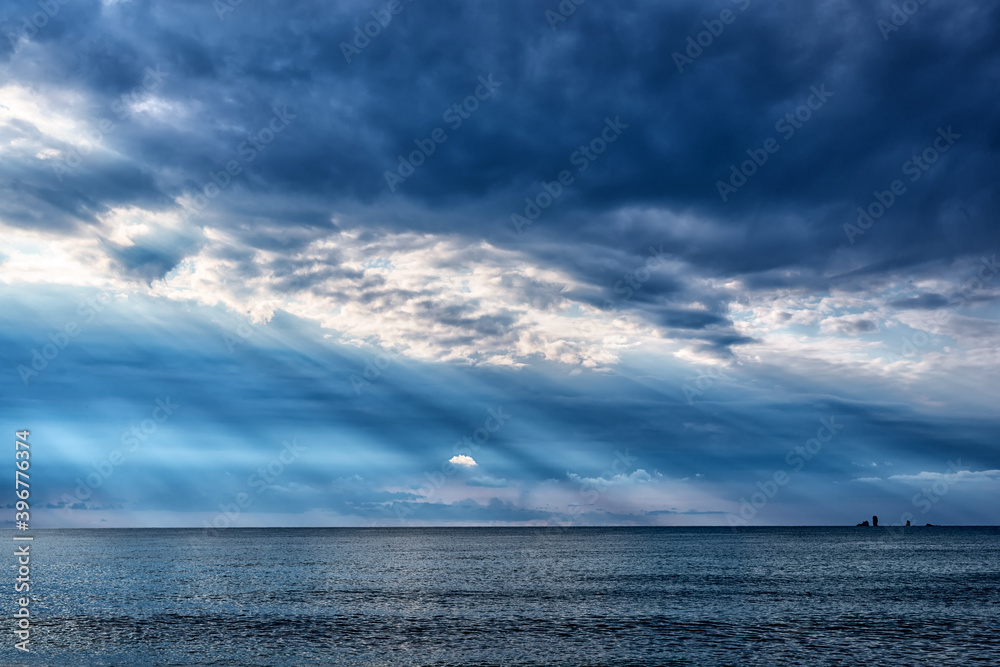 Diagonal sun rays under dark clouds over the Black sea in Crimea