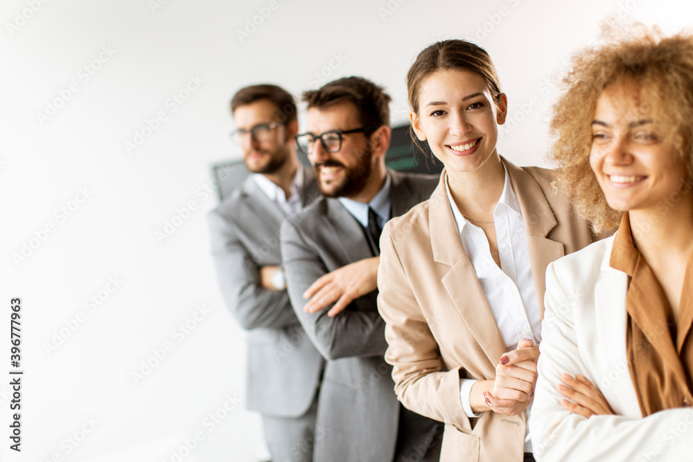 Smiling young business woman standing with group of corporate colleagues in a row together Smiling young business woman standing with group of corporate colleagues in a row together
