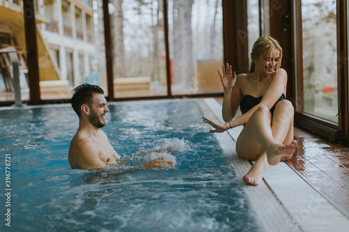 Young couple relaxing on the poolside of interior swimming pool