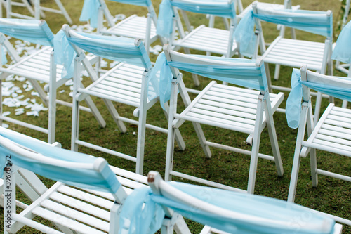 View of white chairs with blue ribbons in a wedding