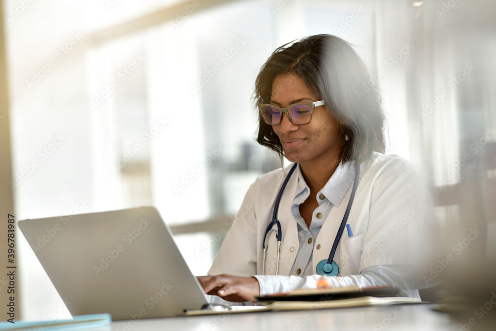 Woman doctor working in office with laptop computer; wearing face mask Woman doctor working in office with laptop computer; wearing face mask