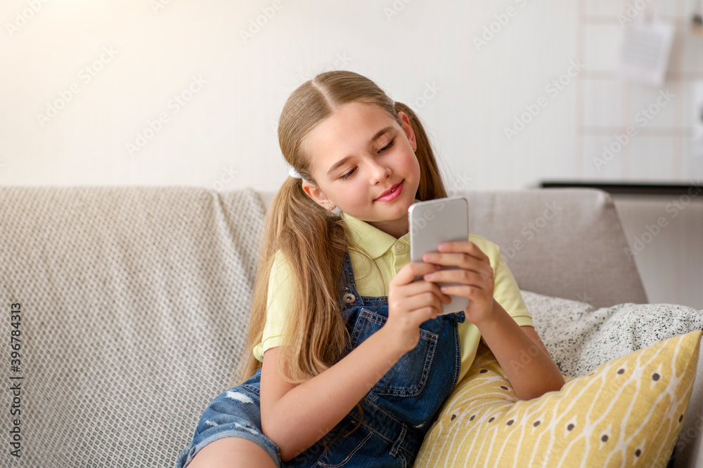 Girl using her smartphone resting on sofa Girl using her smartphone resting on sofa