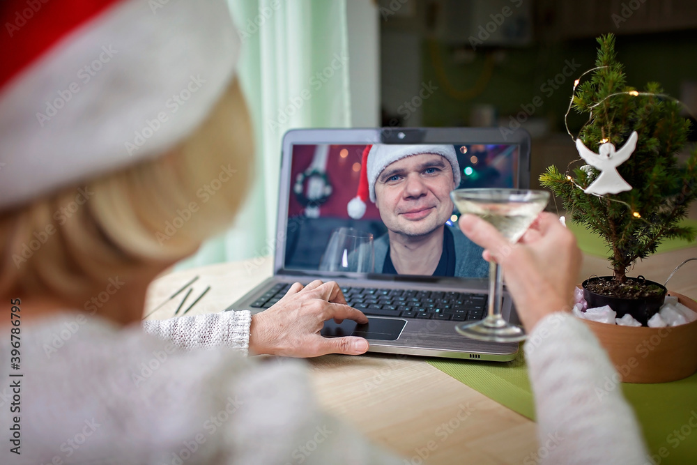 Online celebration. Woman with glass of wine celebrating Christmas with her family via internet Online celebration. Woman with glass of wine celebrating Christmas with her family via internet