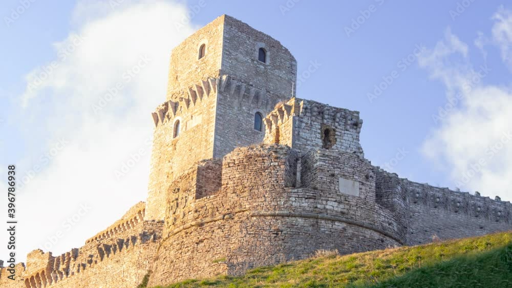 Time lapse of rocca maggiore in assisi during a sunny cloudy day. It is a medievale stone bricks castle with tower up the hill with clouds in background Time lapse of rocca maggiore in assisi during a sunny cloudy day. It is a medievale stone bricks castle with tower up the hill with clouds in background