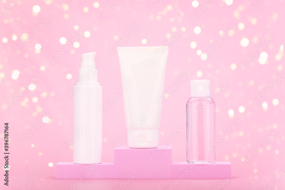 Set of cosmetic products for daily skin care with face cream, cleaning foam and skin lotion on winner pedestal against pink background with yellow bokeh. Concept of cosmetic set gifts and holidays Set of cosmetic products for daily skin care with face cream, cleaning foam and skin lotion on winner pedestal against pink background with yellow bokeh. Concept of cosmetic set gifts and holidays